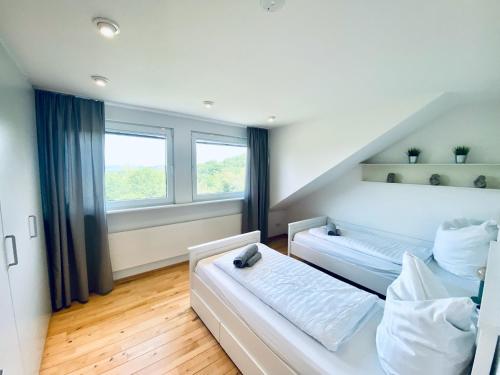 two beds in a room with two windows at Blankensteiner Seeblick in Hattingen