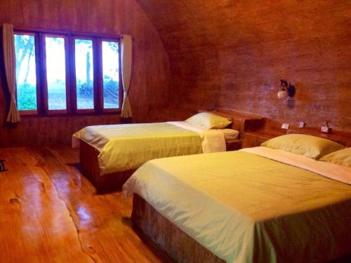 a hotel room with two beds and a window at Ban Tawansongfa in Lang Suan