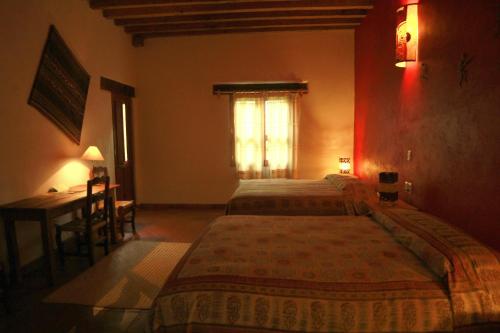 a bedroom with two beds and a desk and a window at Posada Yolihuani in Pátzcuaro