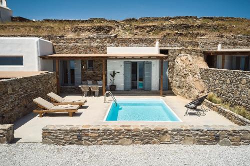 a swimming pool in front of a stone building at Niva Pool Suites in Dhriopís