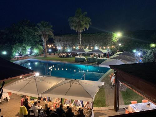 grupa ludzi siedzących w nocy przy basenie w obiekcie Agriturismo Villa Pina w mieście Lizzanello