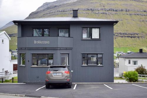 a car parked in a parking lot in front of a building at The Sybilla Apartment - cosy and modern basement apartment in Klaksvík