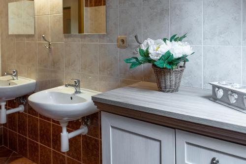 a bathroom with two sinks and a vase of flowers on a counter at Chalupa Bišík in Teplice nad Metují