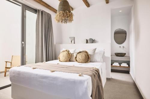 a white bedroom with a white bed and a chandelier at Niva Pool Suites in Dhriopís