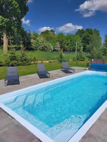 a swimming pool with two lounge chairs in a yard at Gospodarstwo Agroturystyczne z BASENEM & SPA i Alpakami in Ełk