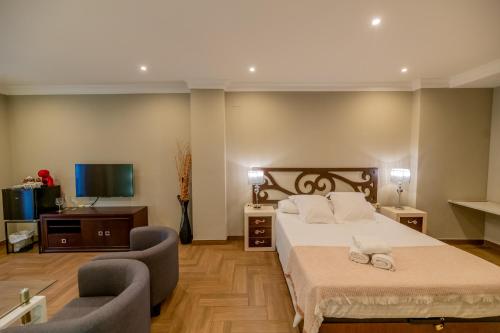 a bedroom with a bed and two chairs and a television at Hotel Monasterio Granada - Adults Only in Granada