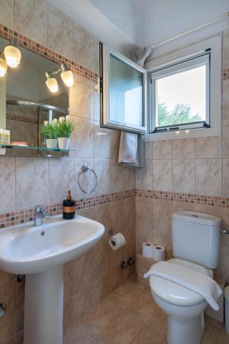 a bathroom with a sink and a toilet and a window at Residence Poseidon in Spartia