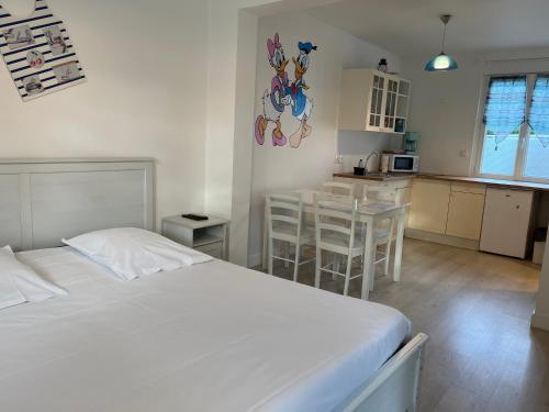 Cet appartement comprend une chambre avec un lit blanc et une cuisine. dans l'établissement Gîtes Poirier Bazin, à Montry