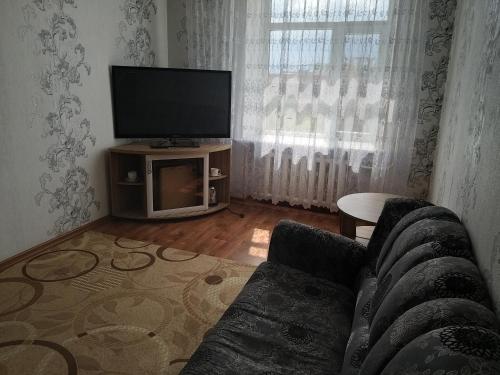 a living room with a couch and a flat screen tv at Гостиница Караганда in Karagandy