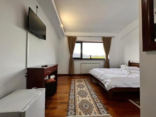a bedroom with a bed and a tv and a window at Belvedere Resort Moieciu in Moieciu de Jos