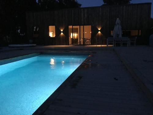 a swimming pool lit up at night at Pool Spa Sauna and Beach Beddingestrand in Beddinge Strand
