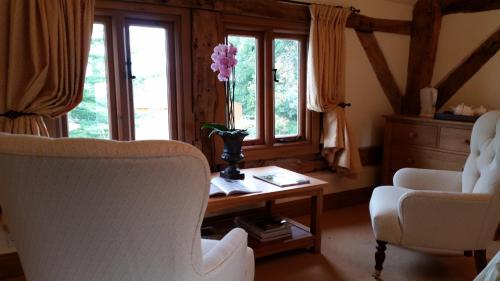 a living room with two chairs and a table with a flower on it at Ty Derw Country House B&B in Ruthin