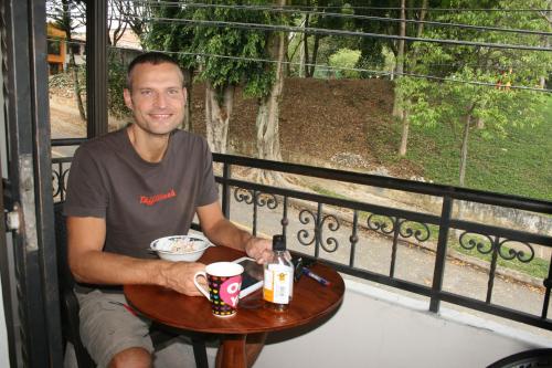 a man sitting at a table on a balcony at Mayorca Homestay in Medellín