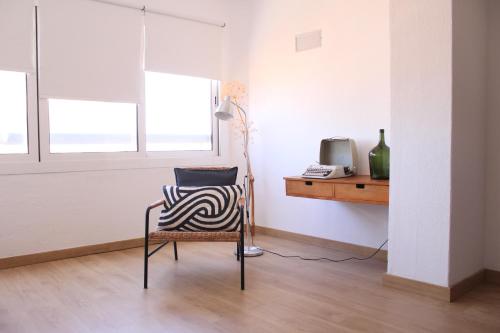 a chair in a room with a desk and a television at A Nossa Casa da Costa in Costa da Caparica