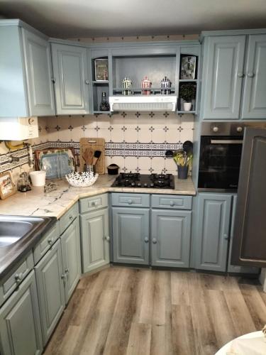 a kitchen with blue cabinets and wooden floors at The Violet House in Costa Nova