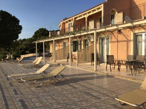 un patio avec des chaises et des tables ainsi qu'un bâtiment dans l'établissement Despina Studios and Apartments, à Lassi