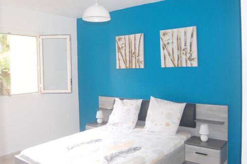 een slaapkamer met een blauwe muur en een bed bij Joli appartement rénové à neuf in Baie-Mahault