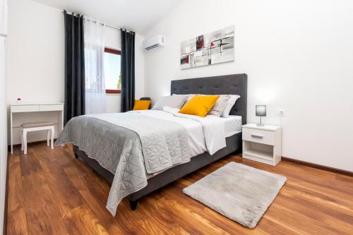 una camera bianca con un grande letto con cuscini gialli di Apartments E&M a Pola (Pula)