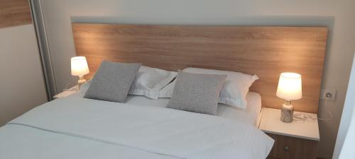 a bedroom with a white bed with two lamps at Luxury apartment Stefanija in Tivat