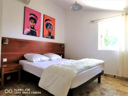 um quarto com uma cama e algumas fotografias na parede em Appartement 16 en duplex, deux chambres - LES SUITES DE ROBINSON - Résidence avec piscine en bord de Siagne, à Mandelieu-La-Napoule em Mandelieu-la-Napoule