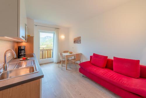 a living room with a red couch in a kitchen at Sandhof Ferienwohnungen in Termeno