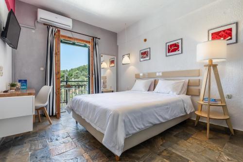 a bedroom with a large bed and a large window at Panormos Beach Hotel Skopelos in Panormos Skopelos