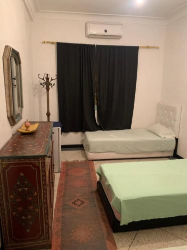 a room with two beds and a table and a window at Dar el Koutoubia in Marrakech