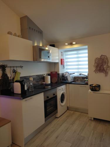 a kitchen with white cabinets and a washer and dryer at Ferragood House - Historic Center in Ferragudo