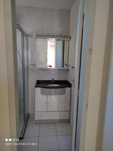 a small bathroom with a sink and a mirror at Apartamento da Fô in Pelotas