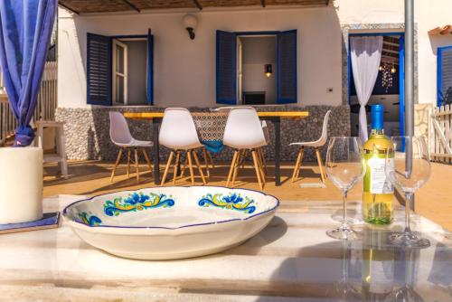 a table with two wine glasses and a bowl on it at Dimore di mare - Beachfront Apartments in Santa Flavia