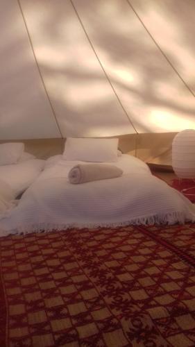 ein weißes Bett in einem Zelt mit einem Teppich in der Unterkunft Quintal Alentejano in Fataca