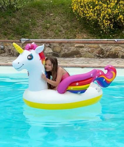 a girl riding on an unicorn raft in a pool at LOCANDA PODERE LE VIGNE in Radda in Chianti