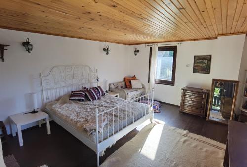 a bedroom with a white bed and a wooden ceiling at Guest house Smolyan in Smolyan