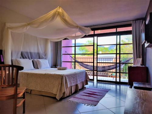 Pousada Zazen في فالي دو كاباو: غرفة نوم بسرير ونافذة كبيرة