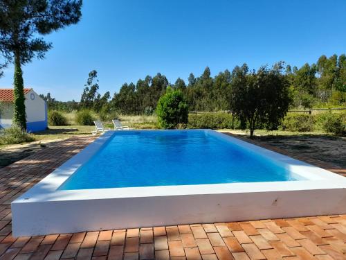 a swimming pool in a backyard with a brick patio at Quintal Alentejano in Fataca