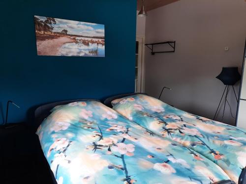 Una cama con una manta con flores. en 't Brugske, en Deurne