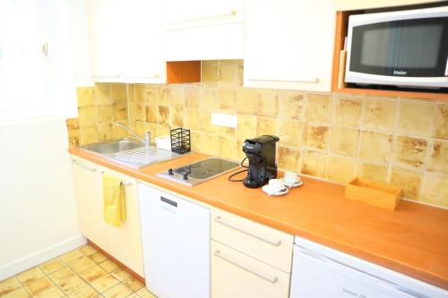 un comptoir de cuisine avec un évier et un micro-ondes dans l'établissement Studio 15 - LES SUITES DE ROBINSON - Résidence avec piscine en bord de Siagne, à Mandelieu-La-Napoule, à Mandelieu-la-Napoule