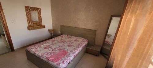 ein kleines Schlafzimmer mit einem Bett und einem Spiegel in der Unterkunft Apparts MT in Sousse