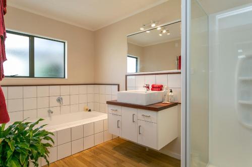 a bathroom with a sink and a tub and a mirror at Lupin Lodge Bed & Breakfast in Taupo