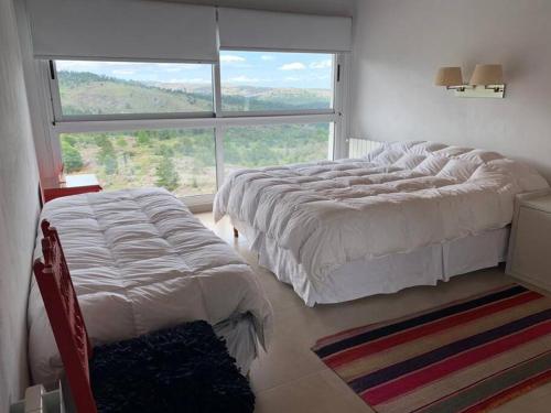 a bedroom with two beds and a large window at La Cumbrecita ,Casona super Lujo . in La Cumbrecita