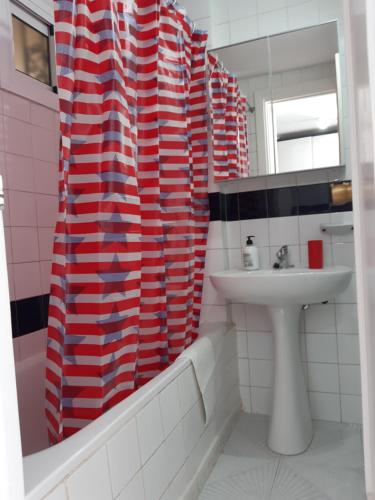 baño con cortina de ducha roja y blanca y lavamanos en Jupiter Apartment Sea, Pools View, en Benalmádena