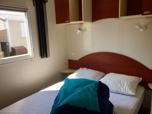 une chambre avec un lit avec une tête de lit en bois et une fenêtre dans l'établissement Mobil-Home 4p Privé Camping 5 étoiles Erdeven 7saints, à Erdeven