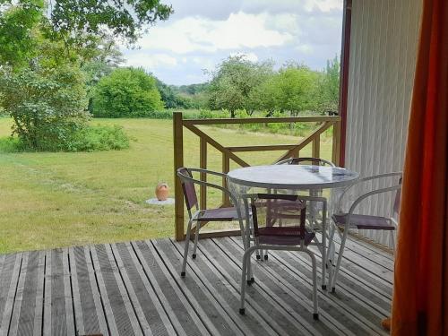 - une table et des chaises sur la terrasse couverte d'une maison dans l'établissement Chalet nature et détente avec piscine, proche zoo de la Flèche et Le Mans, idéal cyclistes et familles - FR-1-410-367, à La Suze-sur-Sarthe