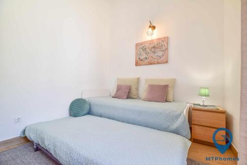 a bedroom with two beds and a night stand with a lamp at Casa TiTeresa in Albufeira