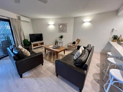 a living room with two couches and a table at Byron Quarter Apartments in Byron Bay
