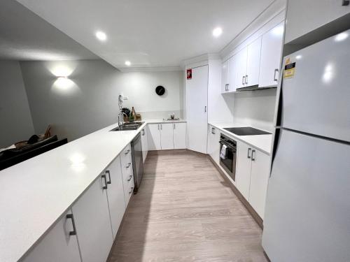 a kitchen with white cabinets and white appliances at Byron Quarter Apartments in Byron Bay
