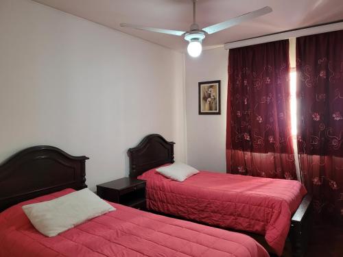 - une chambre avec 2 lits avec des draps rouges et un plafond dans l'établissement Peatonal Sarmiento, à Mendoza
