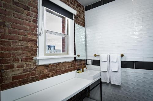 a bathroom with two sinks and a brick wall at H by H Hospitality in Los Angeles