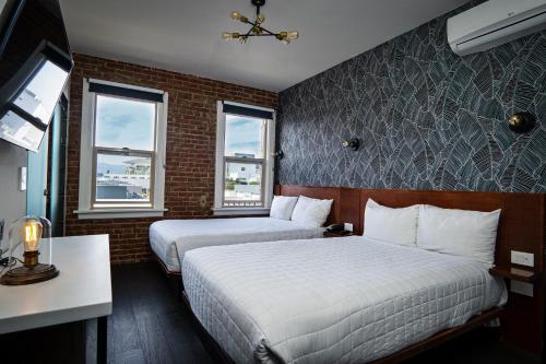a hotel room with two beds and a tv at H by H Hospitality in Los Angeles