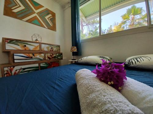 ein Schlafzimmer mit einem blauen Bett und einem großen Fenster in der Unterkunft Acerola in Le Vauclin